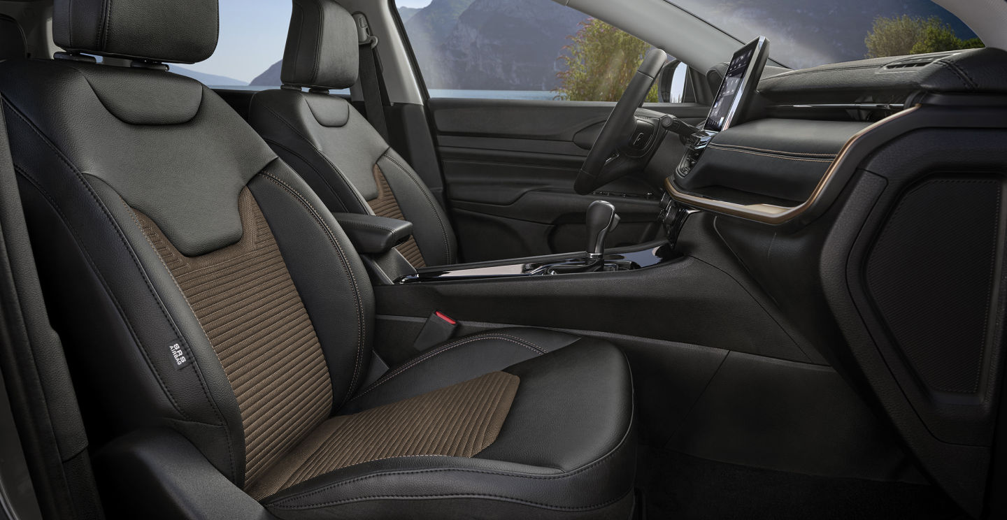 Intérieur raffiné et confortable de la Jeep Compass avec des sièges en cuir noir et des accents en brun, écran tactile et tableau de bord moderne