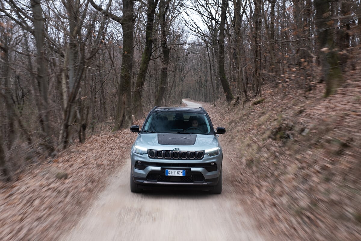 SUV Jeep Compass grise en mouvement sur un chemin forestier en Drôme Ardèche, capturant l'esprit d'aventure et de performance du véhicule.