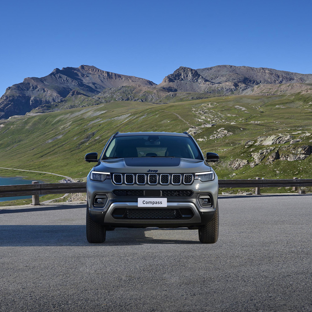 SUV Jeep Compass garée sur une route de montagne avec un paysage alpin impressionnant en arrière-plan, prête pour l'aventure.