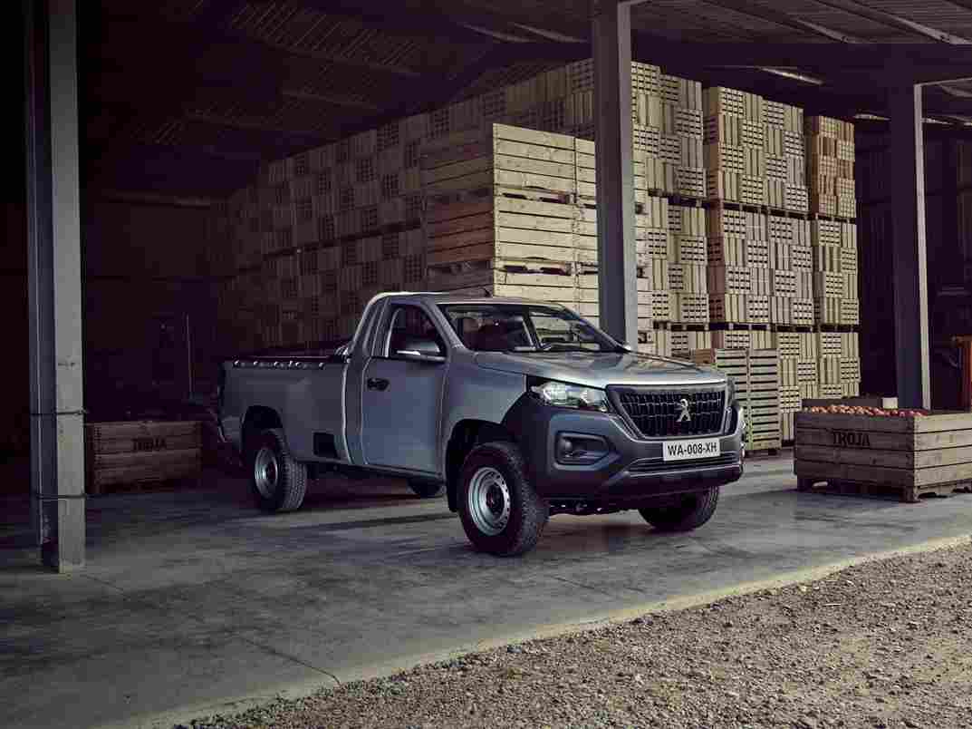  Utilitaire Peugeot Landtrek d'occasion garé dans un entrepôt de caisses en bois, mettant en valeur sa robustesse et sa capacité de chargement, disponible à Valence, Drôme-Ardèche.