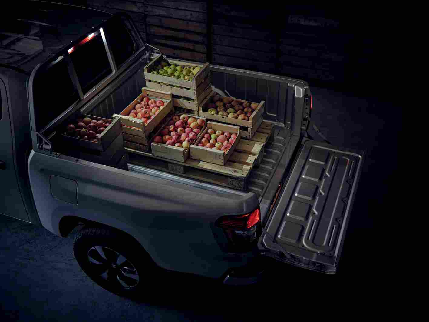 Vue de la benne ouverte d'un utilitaire Peugeot Landtrek d'occasion, chargée de caisses de pommes, démontrant sa capacité de transport, disponible à Valence, Drôme-Ardèche.

