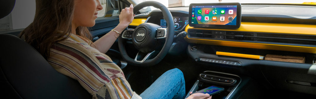 Une femme utilisant les fonctionnalités connectées de l'intérieur moderne d'une Jeep Avenger