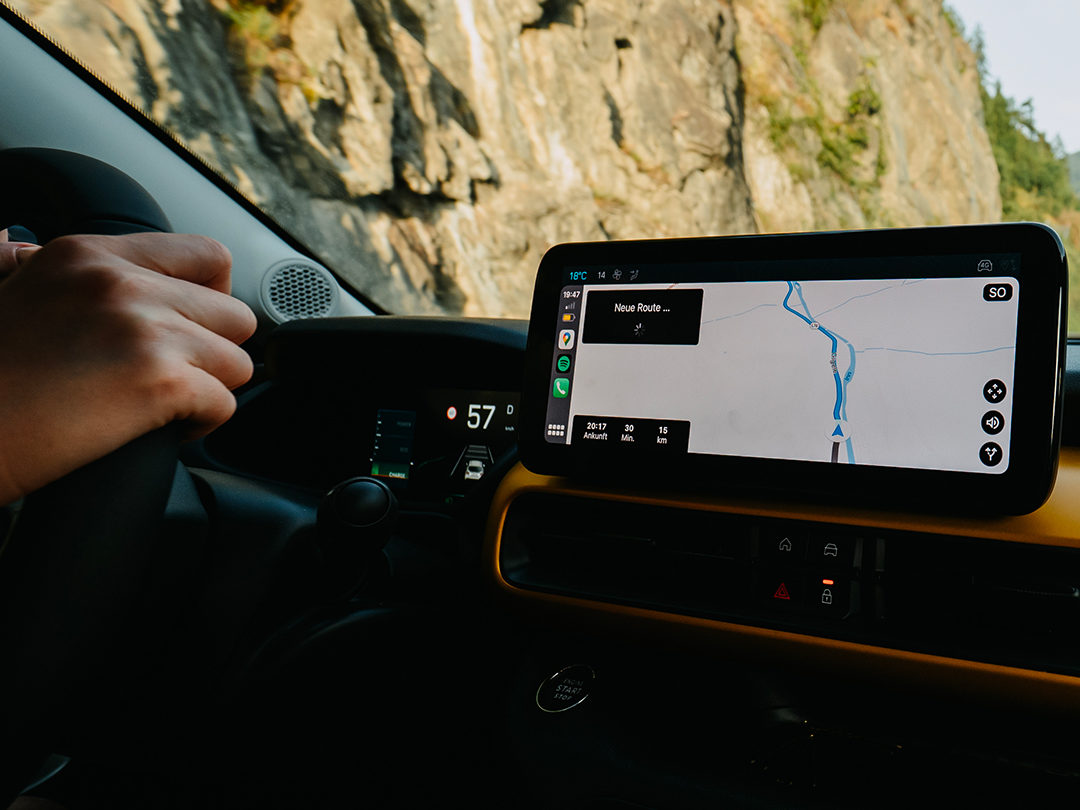 Conducteur utilisant le système de navigation connecté de la Jeep Avenger sur une route de montagne